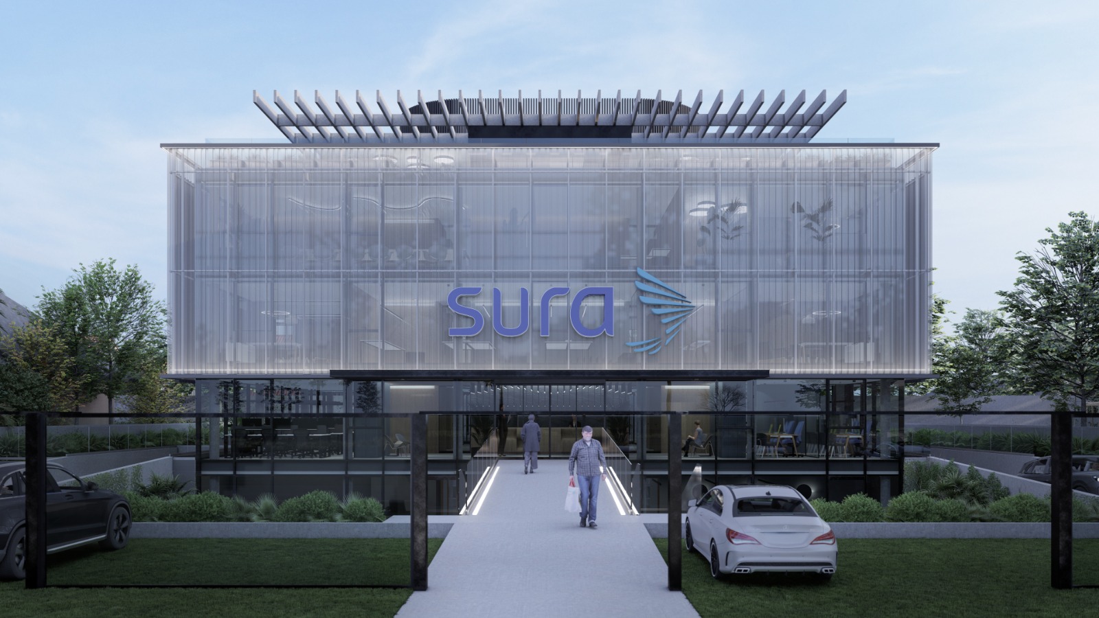 Vista frontal diurna del edificio con su fachada de vidrio y el puente de acceso peatonal